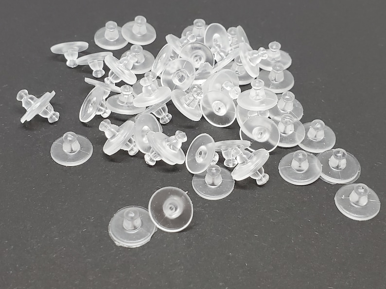 May include: A pile of clear plastic earring backs. The backs are designed to hold earrings in place and are commonly used with stud earrings.