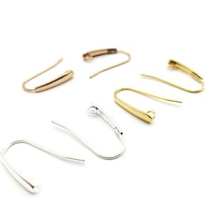 May include: A set of six earring hooks in gold, silver, and rose gold finishes. The hooks are made of metal and have a simple, elegant design.