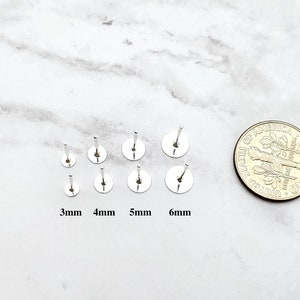 K&ouml;nnte beinhalten: Ein Satz von sechs silbernen Ohrsteckern in verschiedenen Gr&ouml;&szlig;en von 3 mm bis 6 mm. Die Ohrstecker werden neben einer 10-Cent-M&uuml;nze zum Gr&ouml;&szlig;envergleich gezeigt.