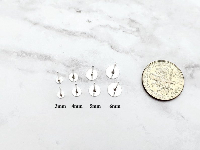 K&ouml;nnte beinhalten: Ein Satz von sechs silbernen Ohrsteckern in verschiedenen Gr&ouml;&szlig;en von 3 mm bis 6 mm. Die Ohrstecker werden neben einer 10-Cent-M&uuml;nze zum Gr&ouml;&szlig;envergleich gezeigt.