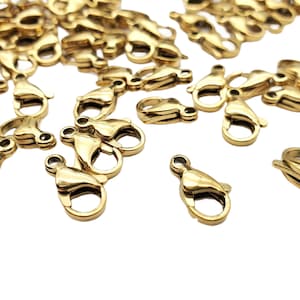 May include: A group of gold-toned metal lobster clasps, commonly used for jewelry making.