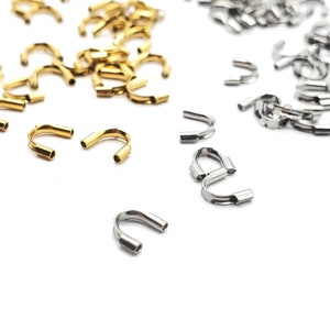 May include: A close-up of two piles of metal jump rings. One pile is gold and the other is silver.