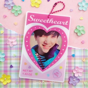 May include: A pink and white Sweetheart keychain with a heart-shaped photo of a smiling person. The keychain has a pink beaded chain and the text "Sweetheart" at the top. The bottom has the text "Net Wt 1.43 OZ" and "My Bias".