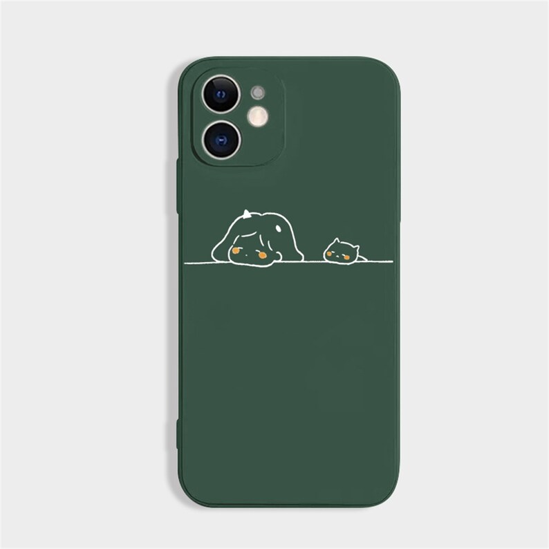 Peut inclure: Coque de t&eacute;l&eacute;phone vert fonc&eacute; avec une illustration fantaisiste de deux personnages de dessins anim&eacute;s. Le plus grand personnage est allong&eacute; et le plus petit est &agrave; c&ocirc;t&eacute;. La coque a une finition lisse et une d&eacute;coupe pour l'appareil photo.