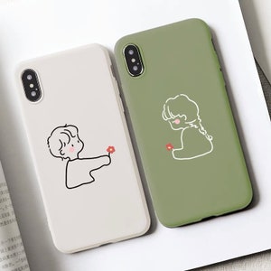 Op de afbeelding: Twee telefoonhoesjes, één witte en één olijfgroene. De witte hoes heeft een zwarte omtrek tekening van een persoon die een rode bloem aanbiedt. De groene hoes heeft een vergelijkbare tekening. Beide hoesjes zijn voor een smartphone.