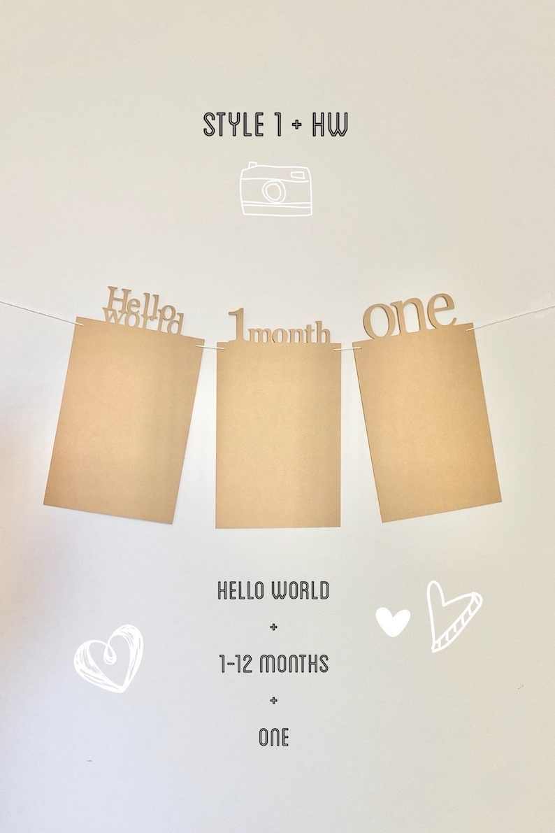 May include: A brown paper banner with the words "Hello World", "1 month", and "one" printed on it. The banner is strung up with white string and there are two white hearts and a white camera drawn on the background.