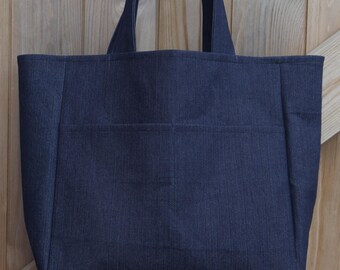 May include: A dark blue denim tote bag with two handles. The bag has a large pocket on the front.