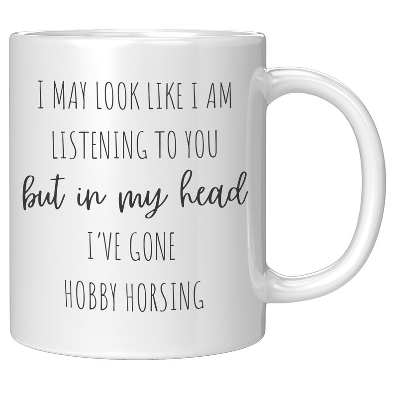 May include: White ceramic coffee mug with black text that reads "I may look like I am listening to you but in my head I've gone hobby horsing."