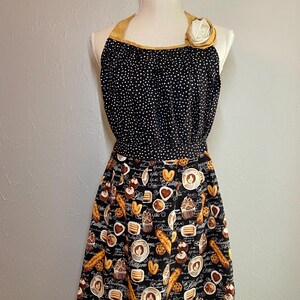 Kitchen apron in a coffee shop and bakery print with a fabric flower at the top.