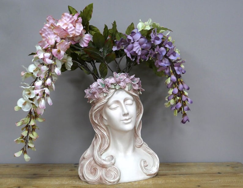 May include: White ceramic planter shaped like a woman's bust with a crown of pink flowers. The planter is decorated with pink and purple flowers.