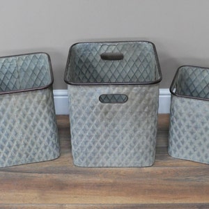 May include: Three galvanised metal storage baskets with a diamond pattern. The baskets are different sizes and are arranged in a row from largest to smallest.