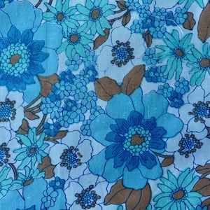 May include: A fabric featuring a dense floral pattern with large and small blossoms in shades of bright blue, light blue, and white. The design includes scattered brown leaves and stems, creating a continuous botanical print across the surface.