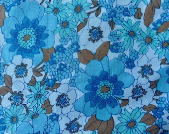 May include: A fabric featuring a dense floral pattern with large and small blossoms in shades of bright blue, light blue, and white. The design includes scattered brown leaves and stems, creating a continuous botanical print across the surface.