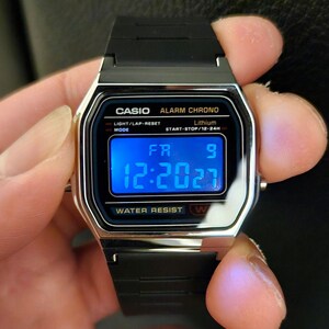 May include: A black digital wristwatch with a silver trim. The watch face displays the time 12:2027, the day of the week FR, and the number 9. The watch also has the words 'CASIO ALARM CHRONO', 'LIGHT/LAP-RESET', 'Lithium', 'MODE', 'START-STOP/12-24', 'WATER RESIST W' printed on the face.