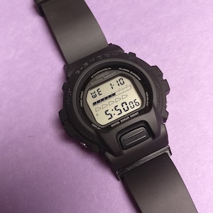 Può includere: Un orologio digitale Casio nero con un cinturino in resina nera. Il quadrante dell'orologio mostra l'ora, la data e il giorno della settimana. L'orologio è resistente all'acqua fino a 20 bar.