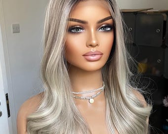 May include: A long, wavy, light blonde wig with a dark blonde root. The wig is styled in loose waves and has a natural-looking parting.