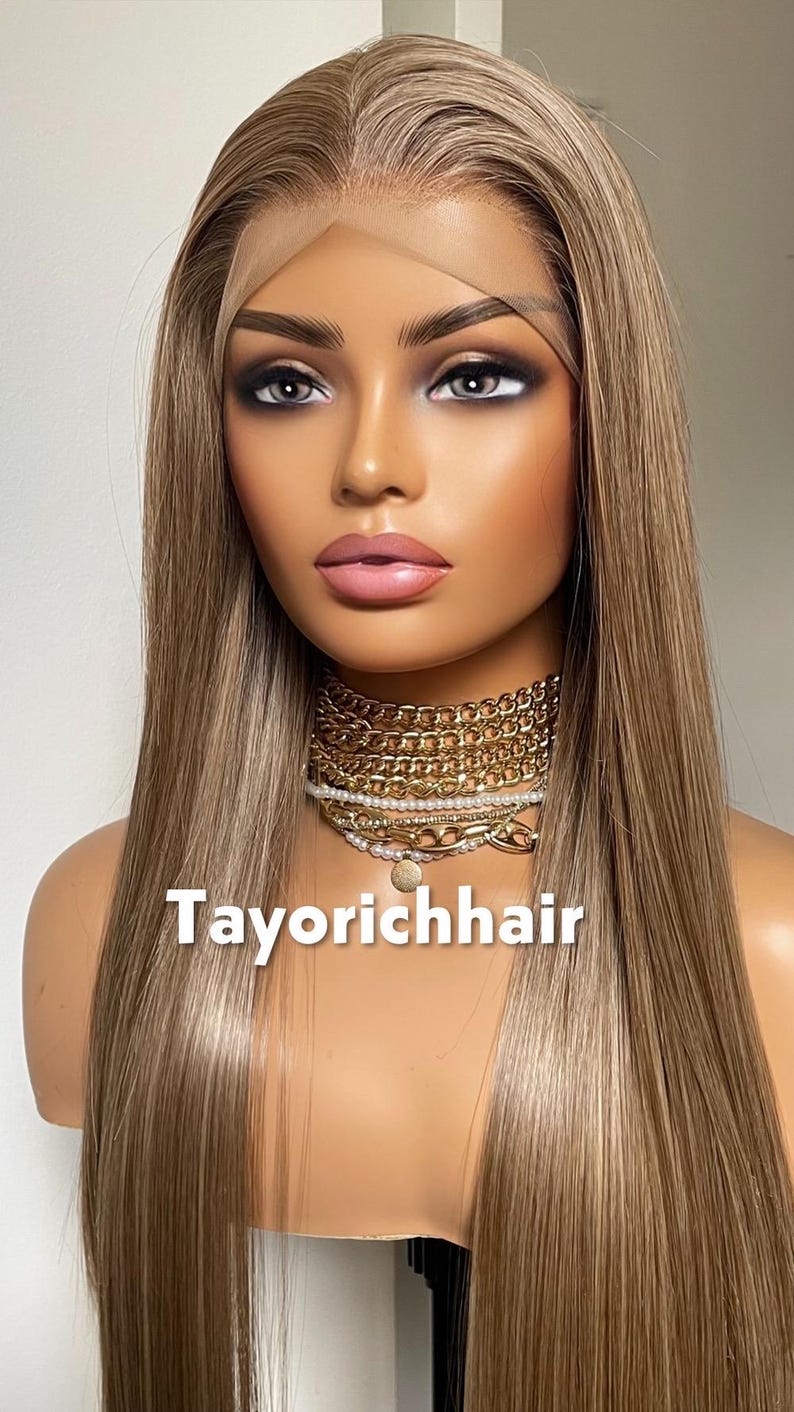 May include: A mannequin head with long, straight, light brown hair. The hair has subtle highlights. The mannequin wears a gold chain necklace and a choker. The text "Tayorichhair" is displayed at the bottom.