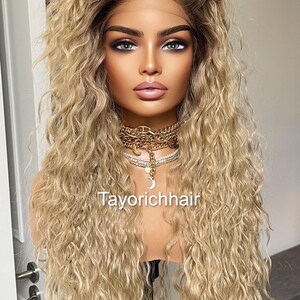 K&ouml;nnte beinhalten: Eine lange, blonde Per&uuml;cke mit lockeren, lockigen Wellen. Die Per&uuml;cke ist auf einem Mannequin-Kopf gestylt und hat einen nat&uuml;rlich aussehenden Haaransatz.