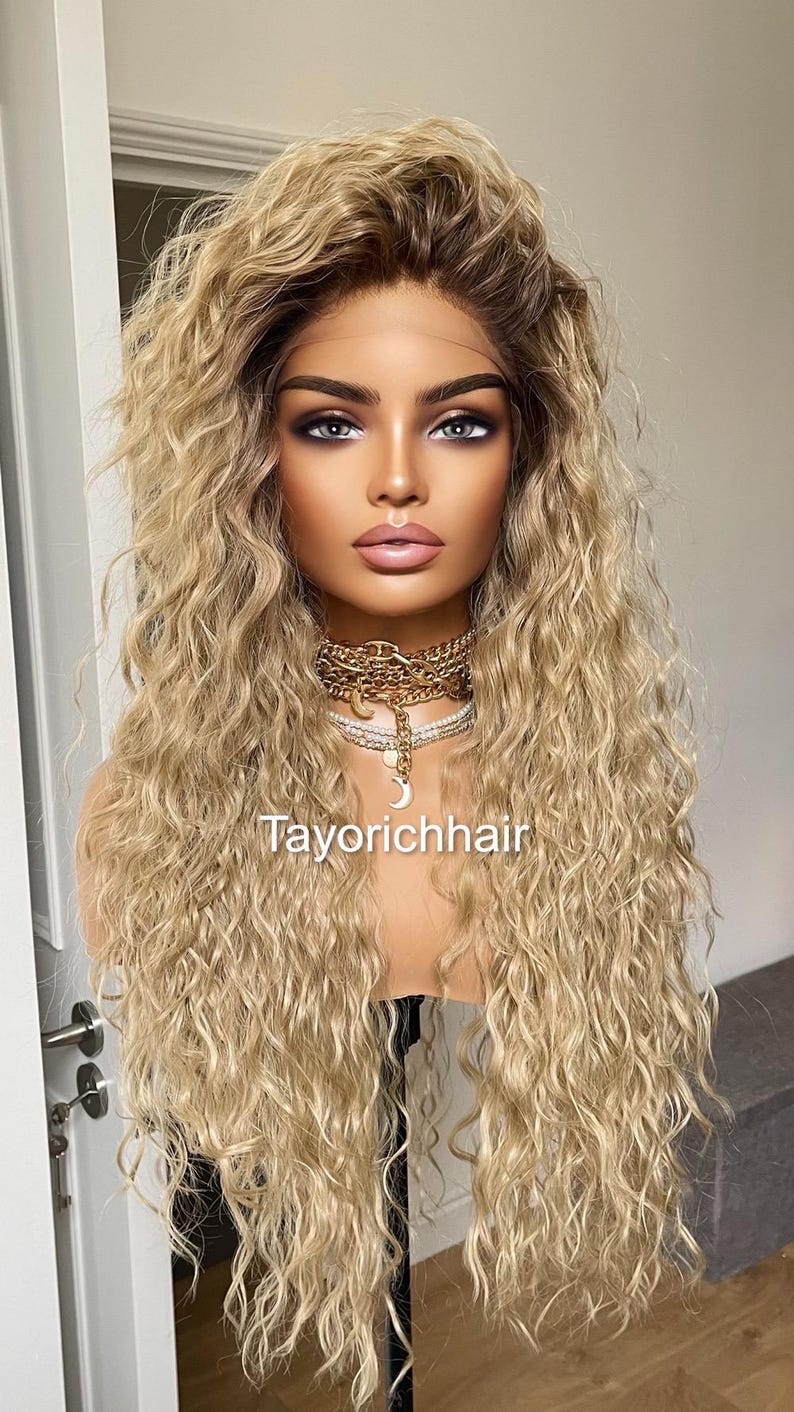K&ouml;nnte beinhalten: Eine lange, blonde Per&uuml;cke mit lockeren, lockigen Wellen. Die Per&uuml;cke ist auf einem Mannequin-Kopf gestylt und hat einen nat&uuml;rlich aussehenden Haaransatz.
