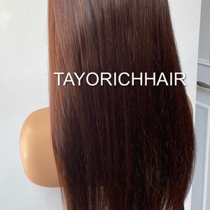 May include: A long, straight, brown human hair wig on a mannequin head. The wig is styled with a center part and falls to the shoulders. The wig is labeled "TAYORICHHAIR".