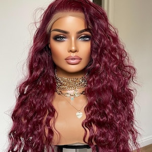 May include: A long, burgundy wig with loose waves. The wig is styled on a mannequin head with a gold necklace.