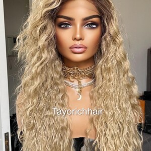 K&ouml;nnte beinhalten: Eine lange, blonde Per&uuml;cke mit lockeren, lockigen Wellen. Die Per&uuml;cke ist auf einem Mannequin-Kopf gestylt und hat einen nat&uuml;rlich aussehenden Haaransatz. Die Per&uuml;cke ist mit einem Mittelscheitel gestylt und f&auml;llt bis zu den Schultern. Die Per&uuml;cke ist mit einem Mittelscheitel gestylt und f&auml;llt bis zu den Schultern. Die Per&uuml;cke ist mit einem Mittelscheitel gestylt und f&auml;llt bis zu den Schultern.