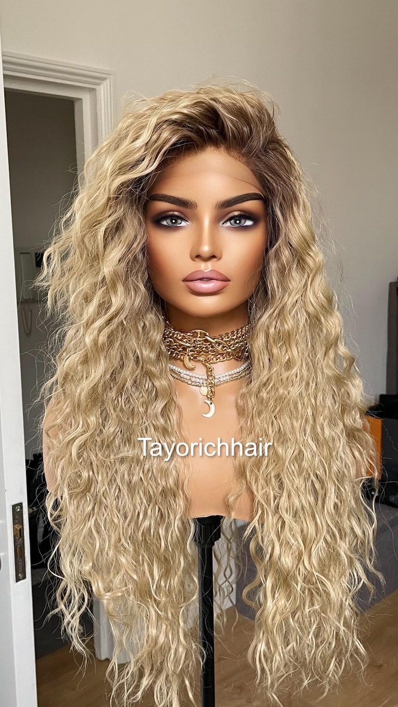 K&ouml;nnte beinhalten: Eine lange, blonde Per&uuml;cke mit lockeren, lockigen Wellen. Die Per&uuml;cke ist auf einem Mannequin-Kopf gestylt und hat einen nat&uuml;rlich aussehenden Haaransatz. Die Per&uuml;cke ist mit einem Mittelscheitel gestylt und f&auml;llt bis zu den Schultern. Die Per&uuml;cke ist mit einem Mittelscheitel gestylt und f&auml;llt bis zu den Schultern. Die Per&uuml;cke ist mit einem Mittelscheitel gestylt und f&auml;llt bis zu den Schultern.