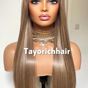May include: A long, straight wig with blonde and light brown highlights is displayed on a mannequin head. The wig has a lace front and is styled with a center part. The text "Tayorichhair" is displayed on the mannequin.