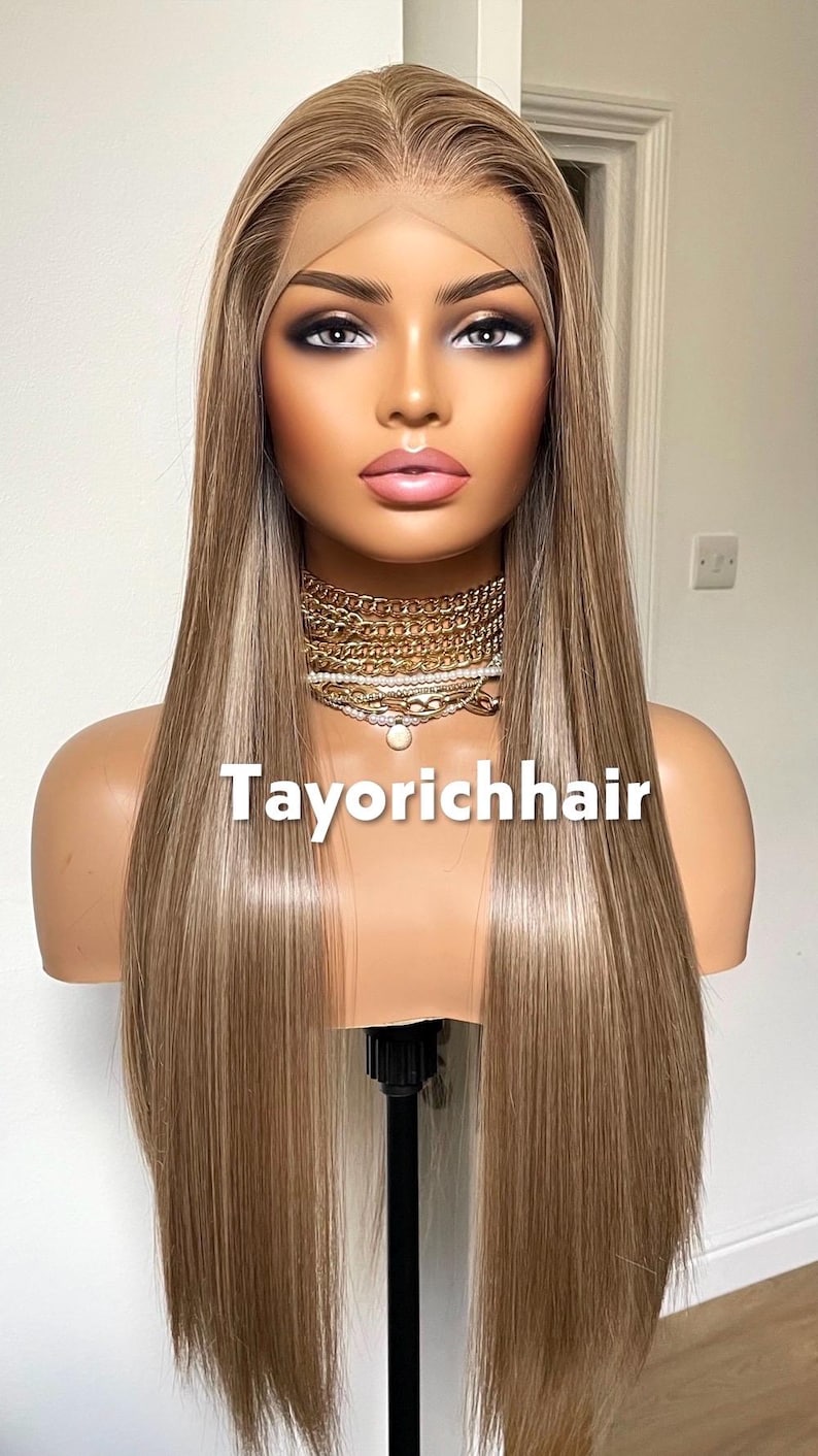 May include: A long, straight wig with blonde and light brown highlights is displayed on a mannequin head. The wig has a lace front and is styled with a center part. The text "Tayorichhair" is displayed on the mannequin.