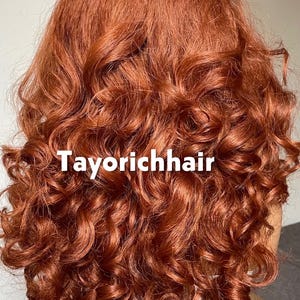 May include: A vibrant, auburn-colored wig with voluminous, tightly curled ringlets. The text "Tayorichhair" is displayed in white across the image. The wig appears to be styled with a deep part and cascading curls.