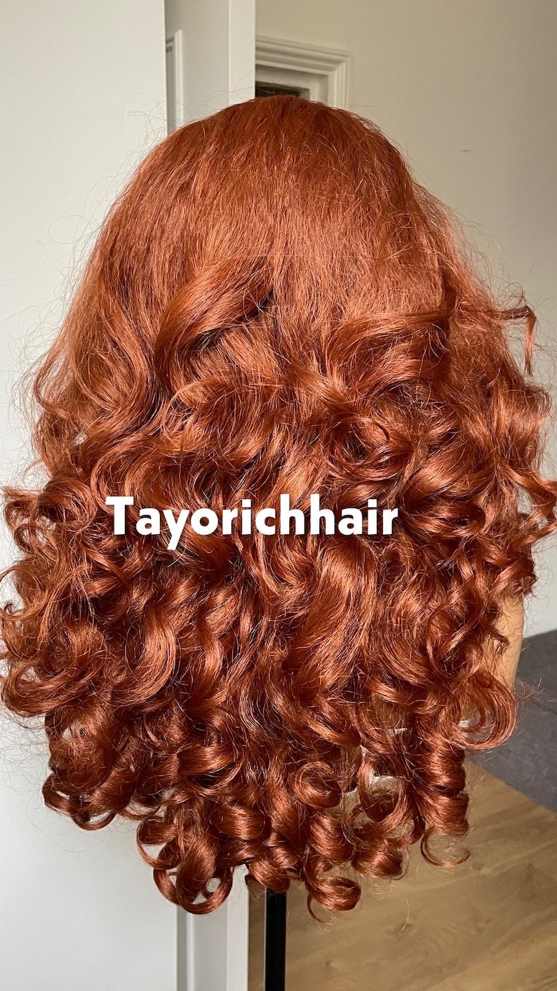 May include: A vibrant, auburn-colored wig with voluminous, tightly curled ringlets. The text "Tayorichhair" is displayed in white across the image. The wig appears to be styled with a deep part and cascading curls.
