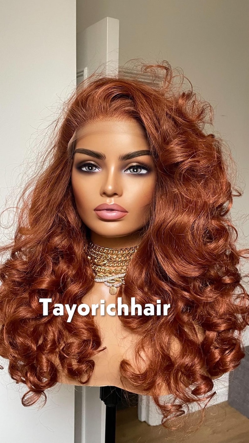 May include: A mannequin head with a copper-colored, curly wig. The wig features a lace front and voluminous curls. The mannequin wears a gold necklace. The text "Tayorichhair" is displayed at the bottom of the image.