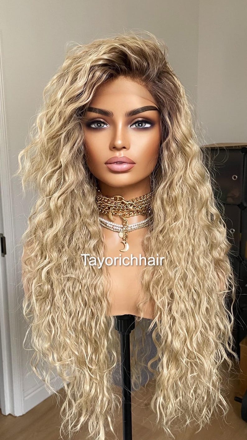 K&ouml;nnte beinhalten: Eine lange, blonde Per&uuml;cke mit lockeren, welligen Locken. Die Per&uuml;cke ist auf einem Mannequin-Kopf gestylt und hat eine nat&uuml;rlich aussehende Farbe.