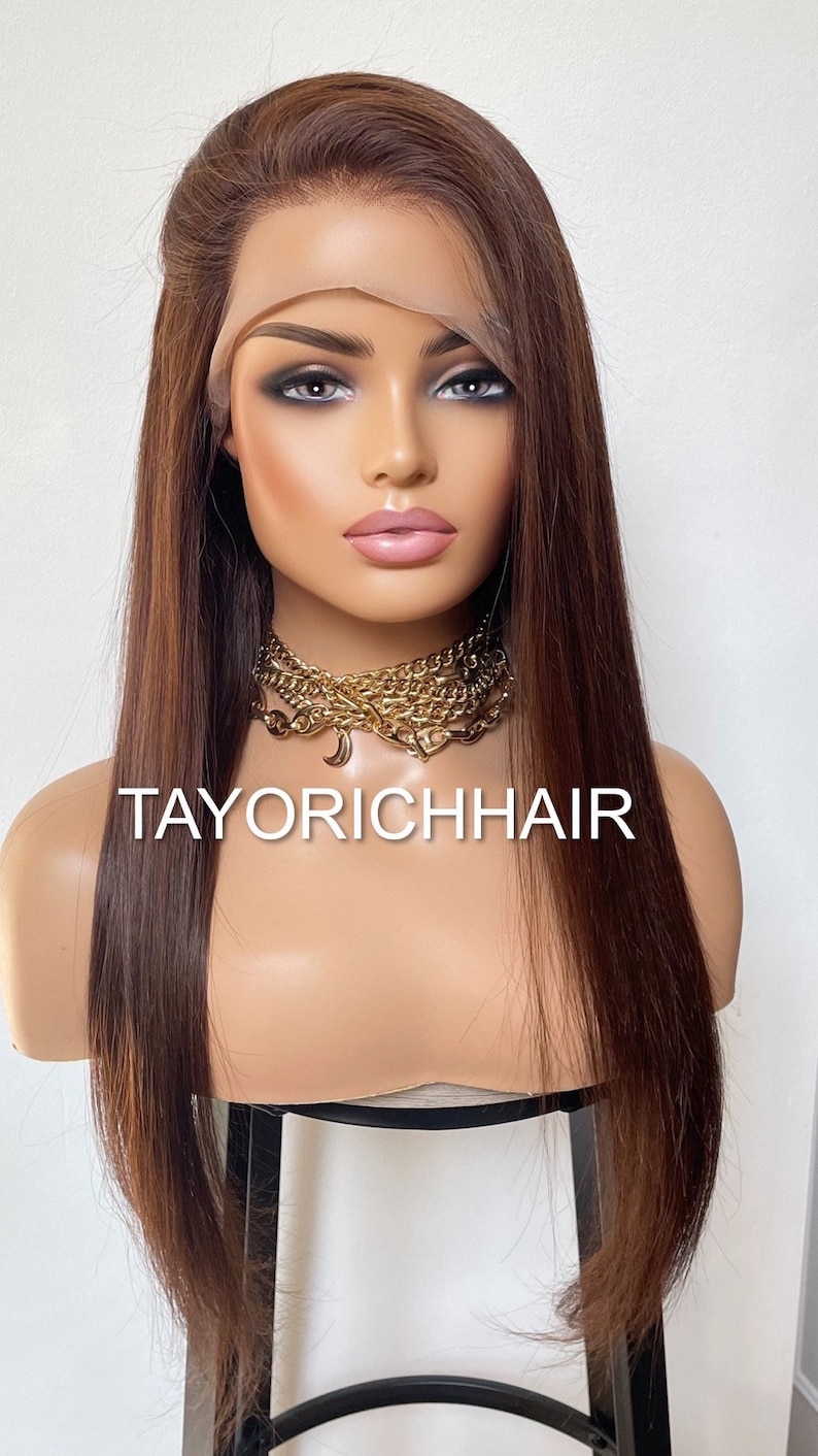 May include: A long, straight, brown human hair wig with a lace front. The wig is styled with a side part and is worn on a mannequin head. The mannequin is wearing a gold chain necklace with a crescent moon charm. The text "TAYORICHHAIR" is visible on the mannequin's chest.