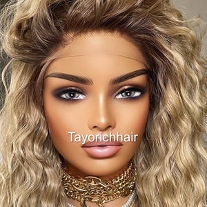 K&ouml;nnte beinhalten: Eine blonde, wellige Per&uuml;cke mit einem Spitzenfront. Die Per&uuml;cke ist in lockeren Wellen gestylt und hat einen nat&uuml;rlich aussehenden Haaransatz. Die Per&uuml;cke wird von einer Mannequin mit neutralem Gesichtsausdruck getragen. Die Mannequin tr&auml;gt eine goldene Kettenkette und eine Perlenkette.