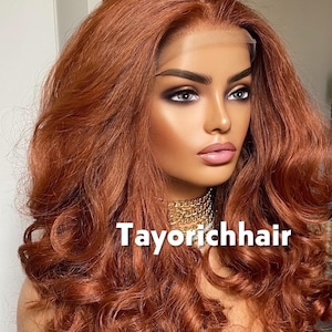 May include: A mannequin head displaying a long, wavy auburn wig. The wig features a lace front and voluminous curls. A gold chain necklace is visible. The text "Tayorichhair" is displayed on the image.