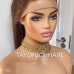 May include: A light brown human hair wig with a lace front and a ponytail. The wig is on a mannequin head and has a nude-colored wig band. The text "TAYORICHHAIR" is visible on the mannequin's chest.