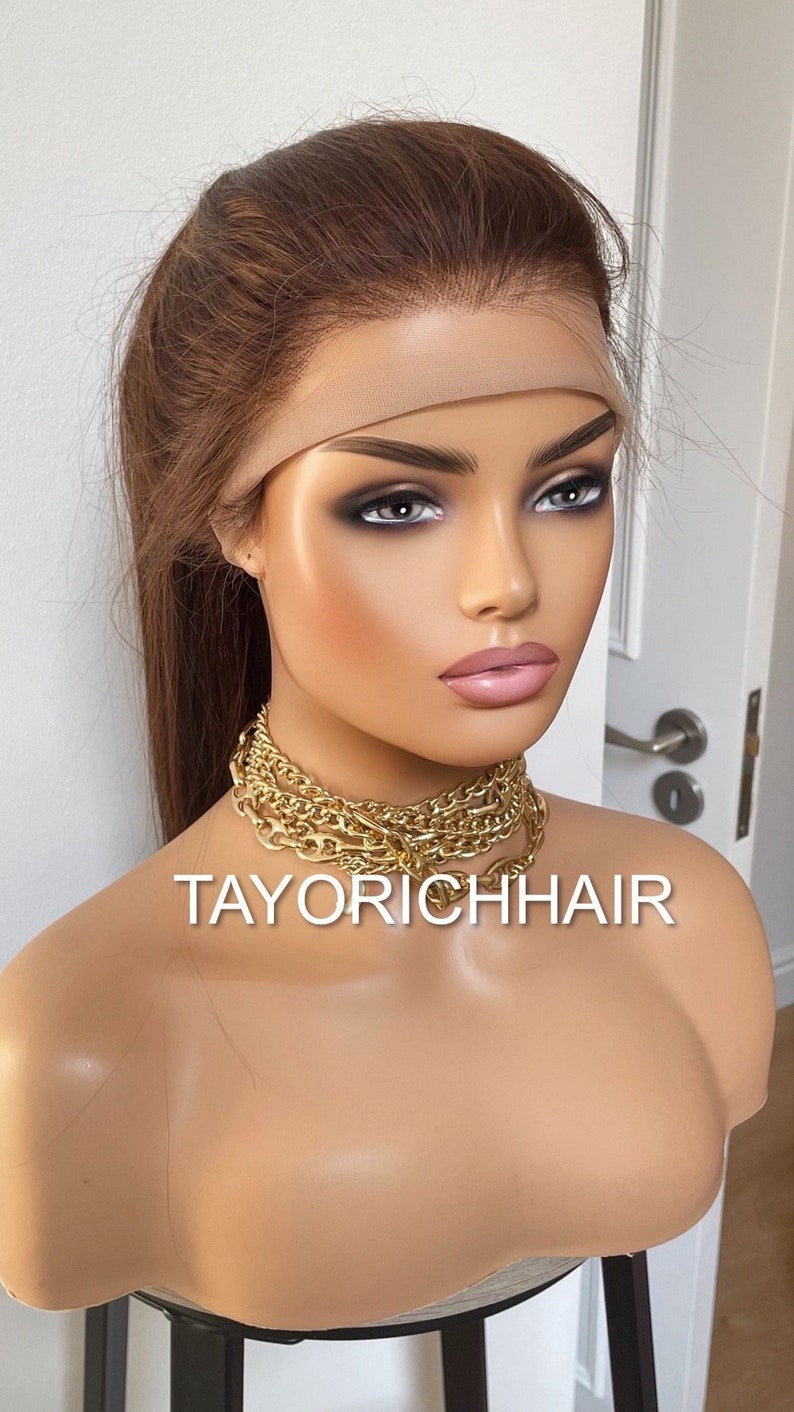 May include: A light brown human hair wig with a lace front and a ponytail. The wig is on a mannequin head and has a nude-colored wig band. The text "TAYORICHHAIR" is visible on the mannequin's chest.