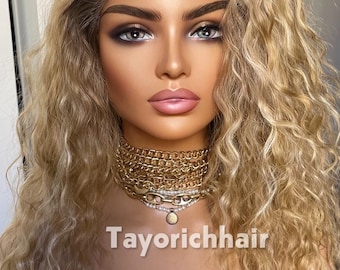 Könnte beinhalten: Eine lange, wellige, blonde Lace-Front-Perücke mit dunklen Ansätzen auf einem Schaufensterpuppenkopf. Die Puppe trägt eine mehrlagige goldene Kettenhalskette mit einem kleinen Anhänger. Der Text Tayorichhair ist unten im Bild weiß aufgedruckt.