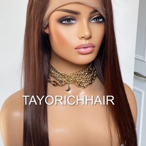May include: A long, straight, brown human hair wig with a lace front. The wig is styled with a side part and falls to the shoulders. The wig is on a mannequin head. The text "TAYORICHHAIR" is visible on the mannequin's chest.