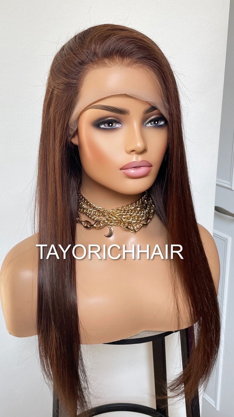 May include: A long, straight, brown human hair wig with a lace front. The wig is styled with a side part and falls to the shoulders. The wig is on a mannequin head. The text "TAYORICHHAIR" is visible on the mannequin's chest.