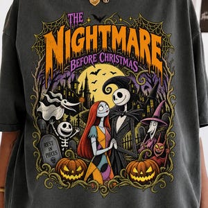 May include: A charcoal gray short-sleeve t-shirt featuring a graphic print of The Nightmare Before Christmas characters including Jack Skellington, Sally, Zero, and pumpkins. The design includes a yellow moon, a haunted house, and text.