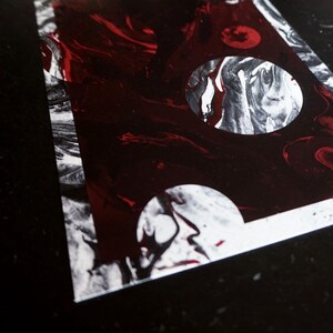 Puede incluir: Un diseño abstracto en blanco y negro con acentos rojos. El diseño presenta dos círculos con un patrón de mármol.