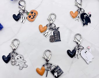 May include: A collection of Halloween-themed charms with silver-tone clasps. Charms include a jack-o'-lantern, ghost, mummy, and a tombstone with the text "Every Day is Halloween". Other charms include hearts, letters, and a trick-or-treat bag.