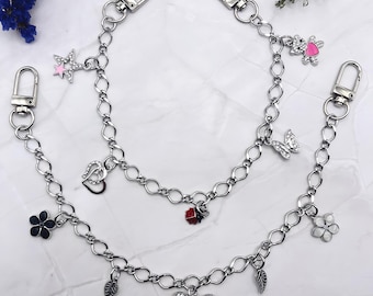 May include: Two silver-toned metal chains featuring lobster claw clasps at each end. The chains are adorned with various charms including a rhinestone star with a pink center, a heart, a butterfly, a ladybug, a flower, a bow, and a bear.