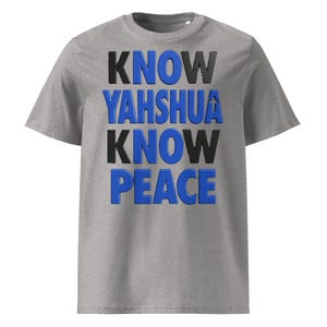 May include: A heather gray short-sleeve t-shirt featuring the text "KNOW YAHSHUA KNOW PEACE" printed in a bold, layered font. The letters alternate between black and blue, with a small cross symbol integrated into the letter A in Yahshua.