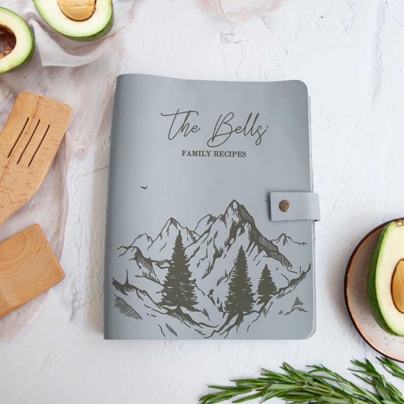 Light gray personalized leather recipe book with mountain landscape engraving and custom family recipe title