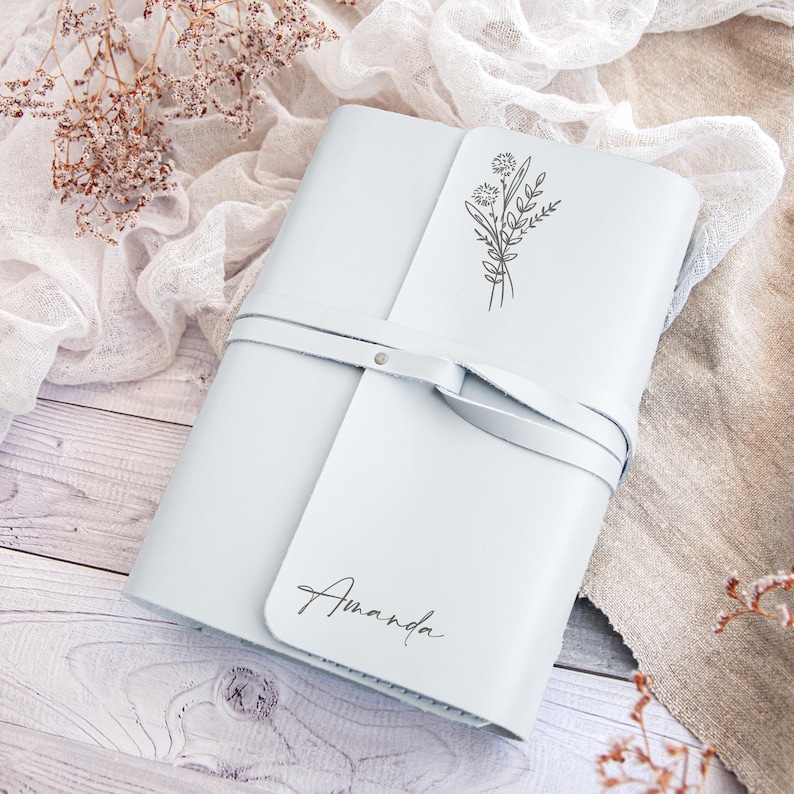 May include: A light blue leather journal with a floral design and the name "Amanda" embossed on the front.