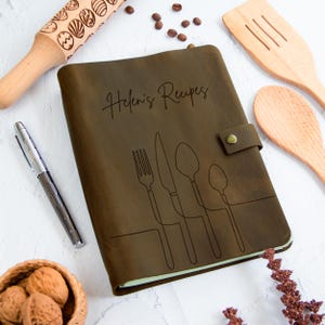 a walnut leather-bound recipe book with a monoline image of a knife, fork, spoon