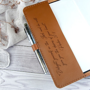 May include: A brown leather journal with a silver pen tucked into the leather strap. The journal has an engraved quote: "Delight yourself in the Lord, and he will give you the desires of your heart." Psalm 37:4